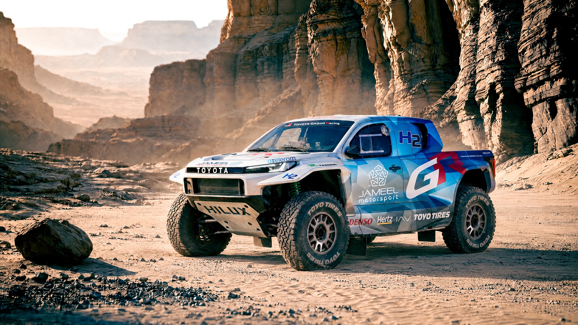 Toyota DKR GR FC Hilux, veículo elétrico a pilha de combustível e que irá participar no Rali Dakar em 2027, fotografado numa perspetiva de 3/4 frontal com o deserto de fundo