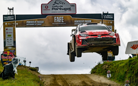 carro de rali da Toyota num salto durante a corrida com publicidade atrás
