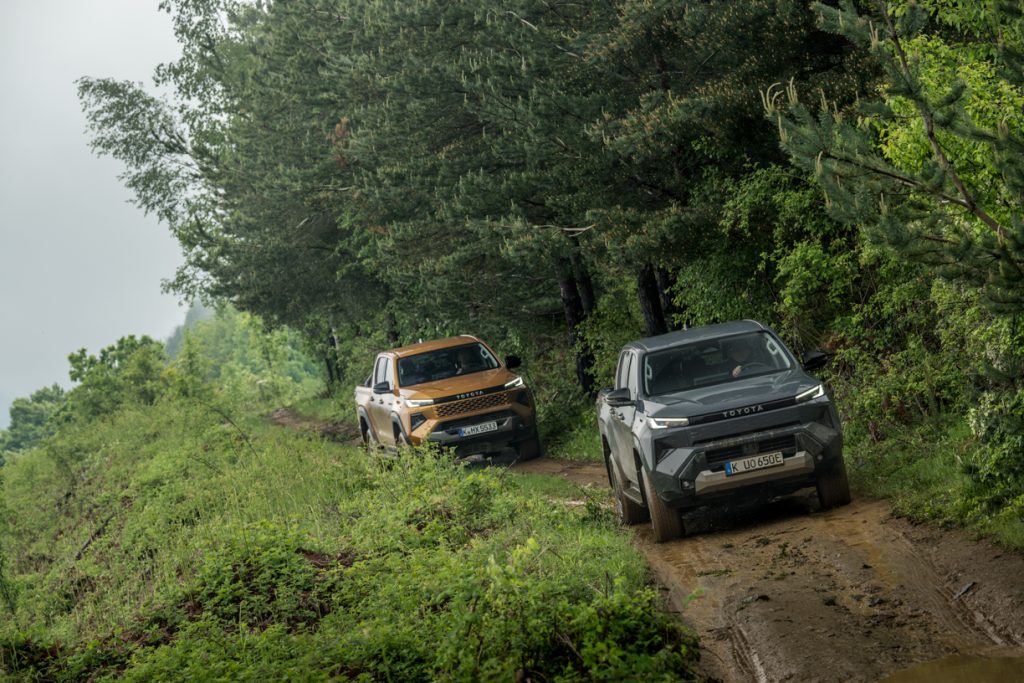 dois veículos hilux da toyota a percorrer em caminhos rurais lamacentos 