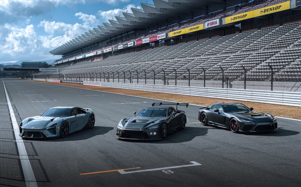 três carros de corrida parados numa pista de competição com a bancada no fundo