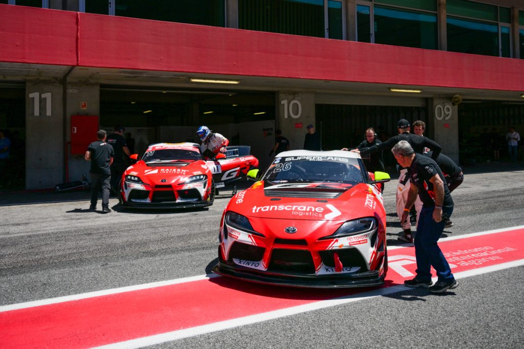 carros de corrida da toyota parados nas garagens com pessoas à volta