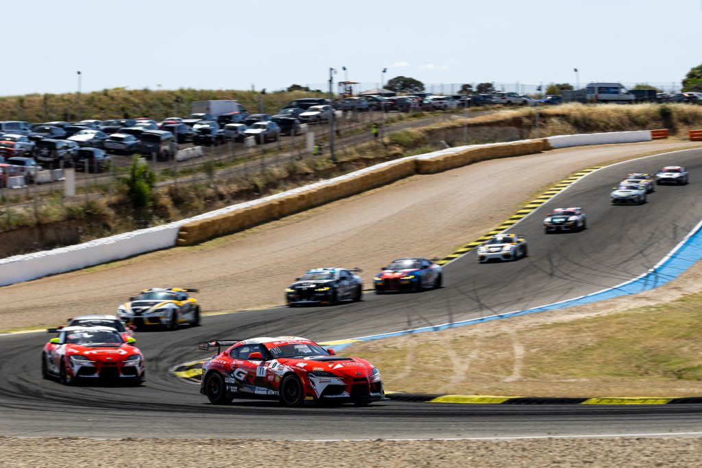 Vista ampla de uma parte do percurso de corrida de veículos com vários carros na pista