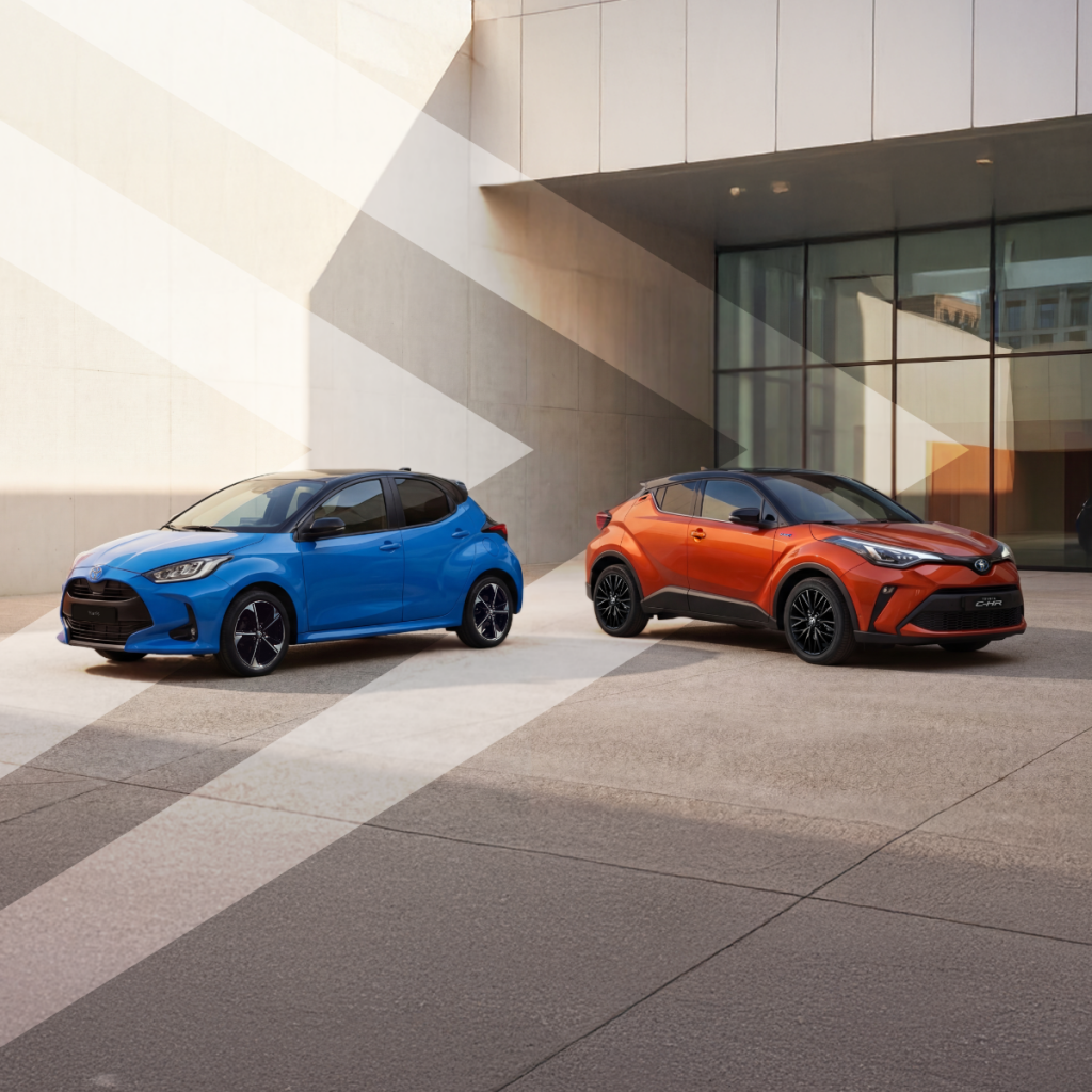 dois veículos da toyota parados num pavimento num ambiente urbanho