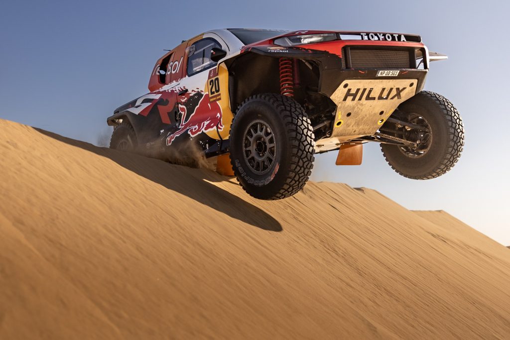 veículo da toyota em ambiente de deserto a saltar uma duna
