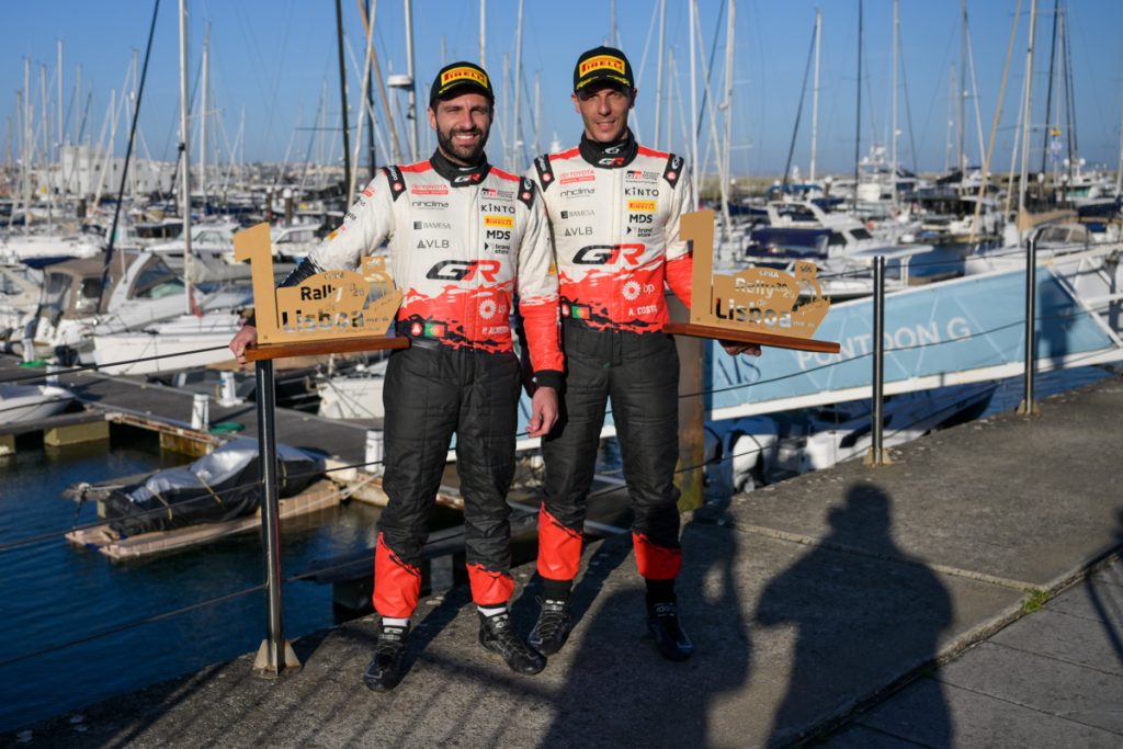 Pilotos Pedro Almeida e António Costa da TOYOTA GAZOO Racing Caetano Portugal fotografados com trofeú com uma marina de fundo, após vencerem o Rali de Lisboa.