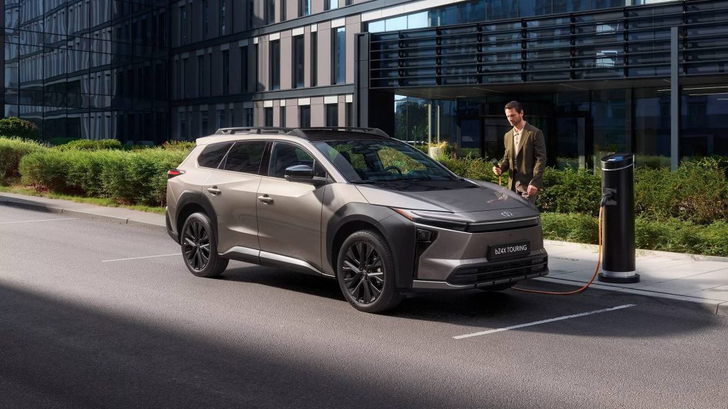 Homem com roupa formal prestes a carregar uma viatura Toyota bZ4X Touring num ambiente citadino