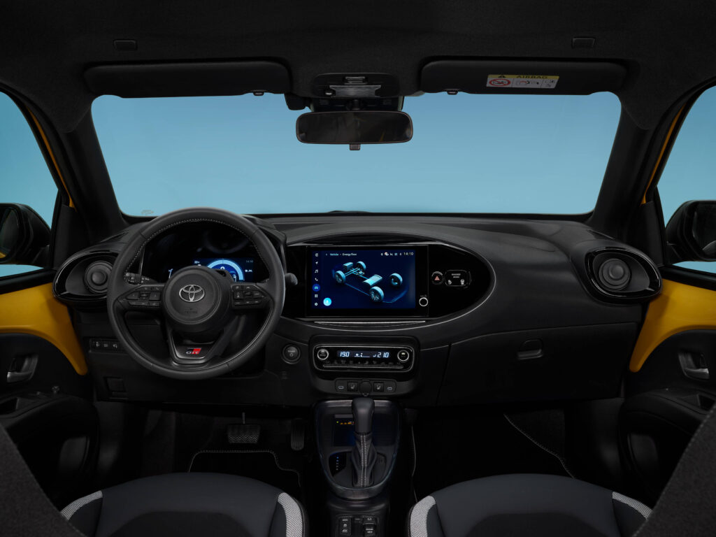 Vista do interior do novo Toyota Aygo X GR Sport. Volante, consola central e parte dos bancos dianteiros são visíveis