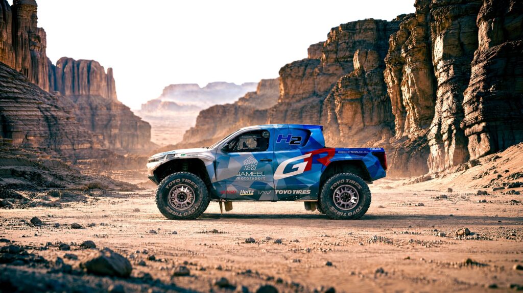 Lateral do Toyota DKR GR FC Hilux fotografada sob uma paisagem desértica, no meio de formações rochosas