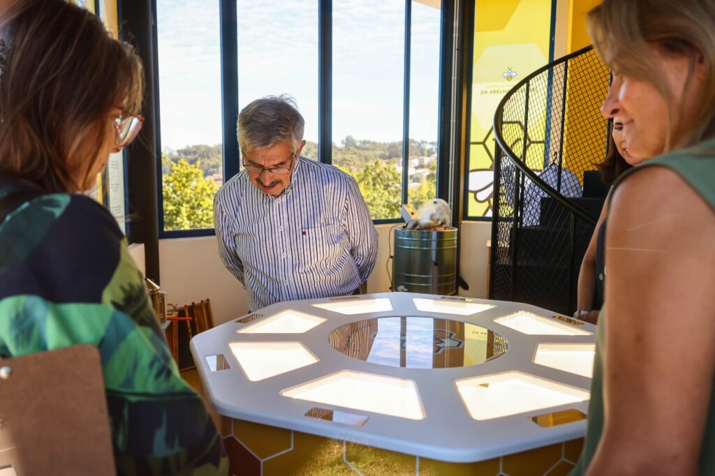 Convidados, incluindo o Presidente e Ceo da Toyota Caetano Portugal José Ramos, à volta do stand em forma de favo de mel no primeiro piso do Centro de Interpretação da Abelha e do Mel