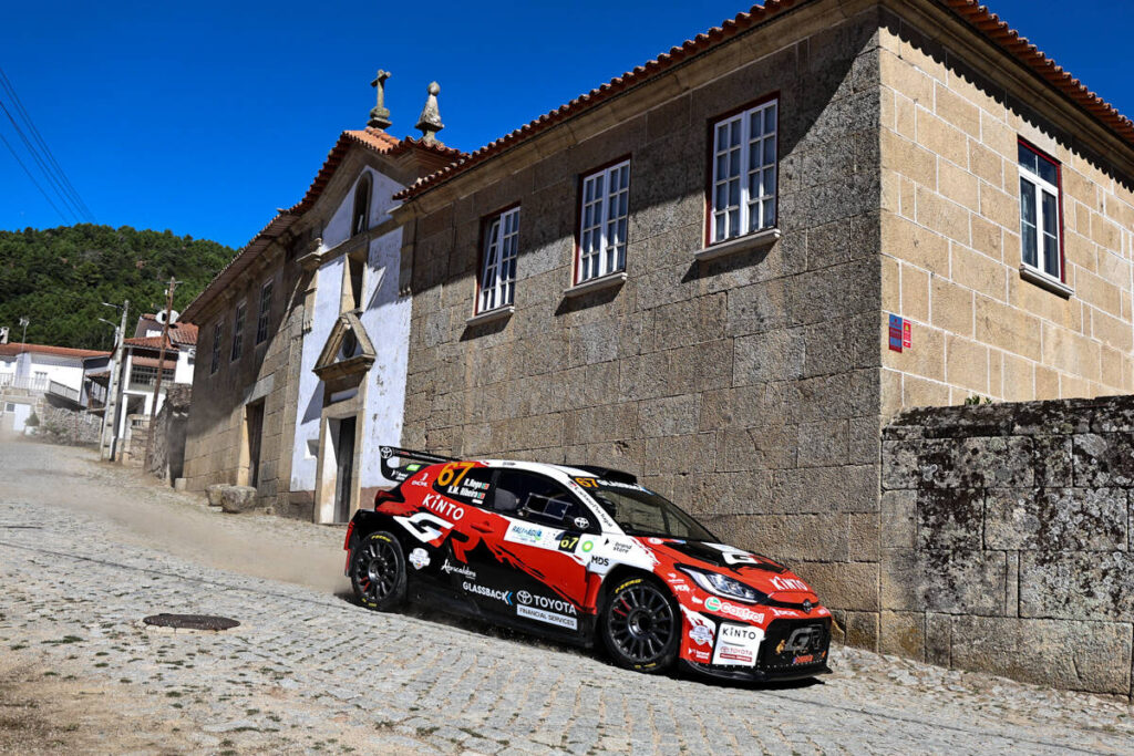 Lateral do Toyota GR Yaris Rally2 do piloto Rafael Rêgo fotografado durante a corrida, enquanto passa por uma capela